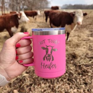 A woman holding a pink cup that has a custom engraving that says "not today Heifer" with cows in the background