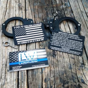 lazerwerk business card with custom blue miranda card laying on wooden table in front of handcuffs