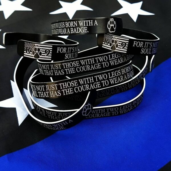 black metal bracelets with K9 verbiage on them laying on a blue flag