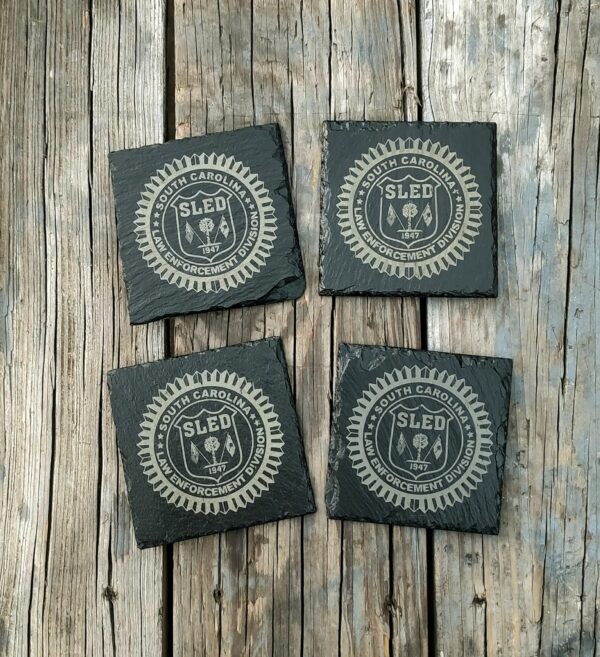 Four coasters laid on a wooden table with the SLED (South Carolina Law Enforcement Devision) logo